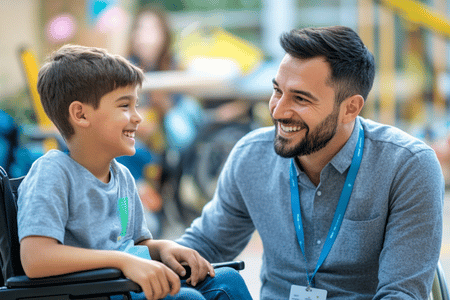 Smiling male therapist talking with a young boy in a wheelchair—illustrating inclusive, supportive learning through Social Story Source’s social stories and life skills resources for children with disabilities.